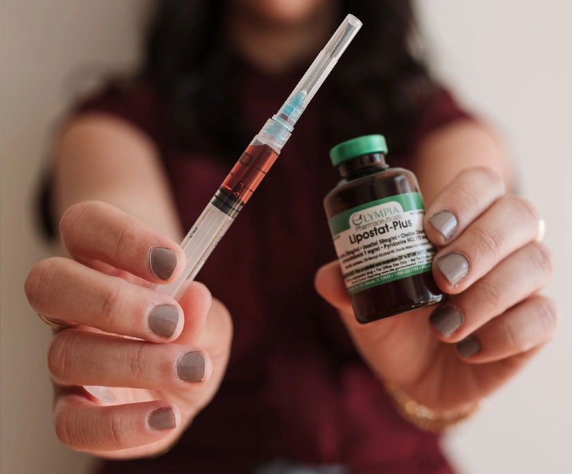 Woman holding syringe and a bottle of injectable vitamin shots