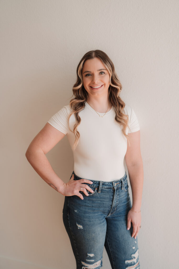 Jax is smiling with her right hand on her hip