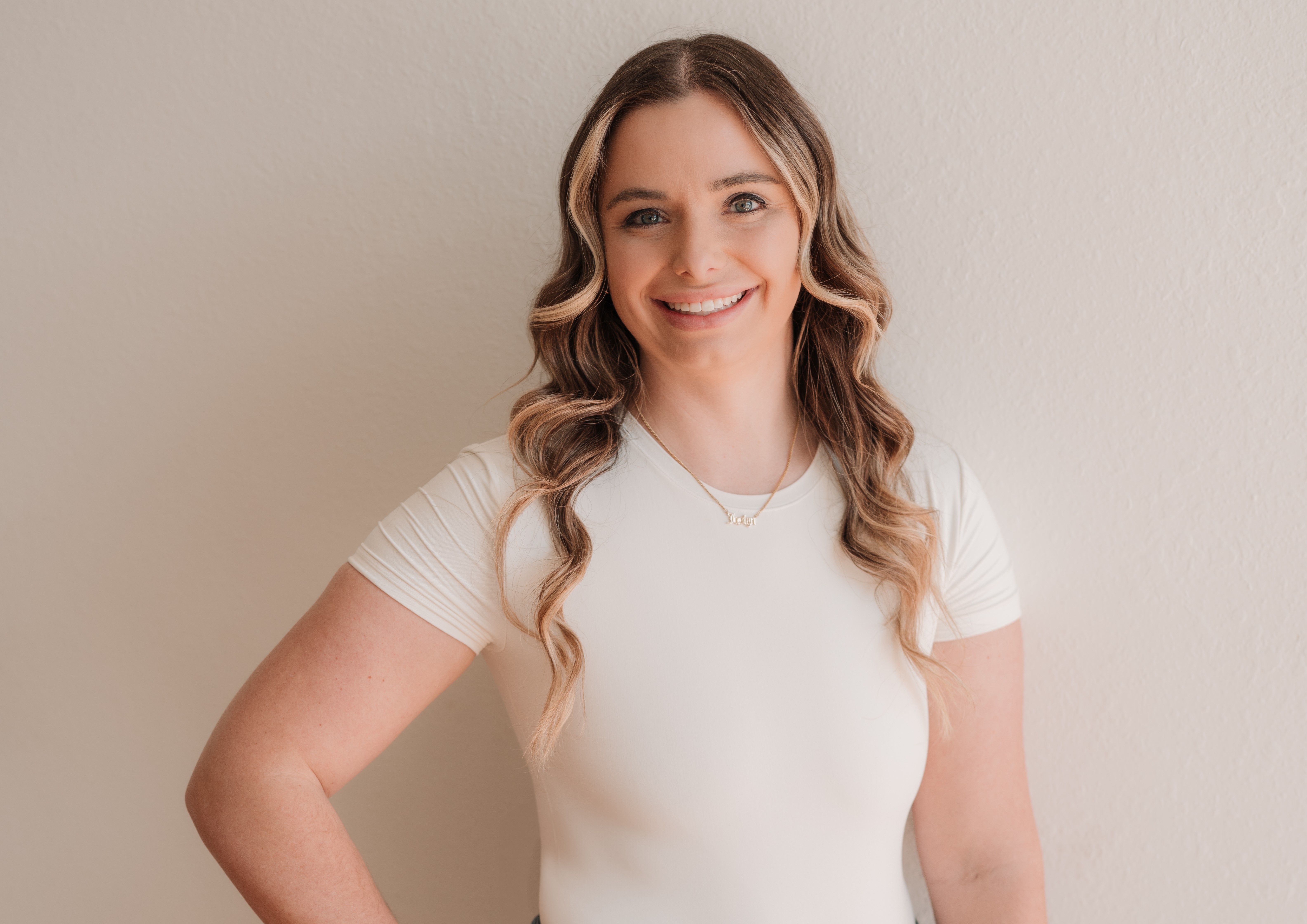 Jax smiling wearing jeans and white shirt with her right hand on her hip